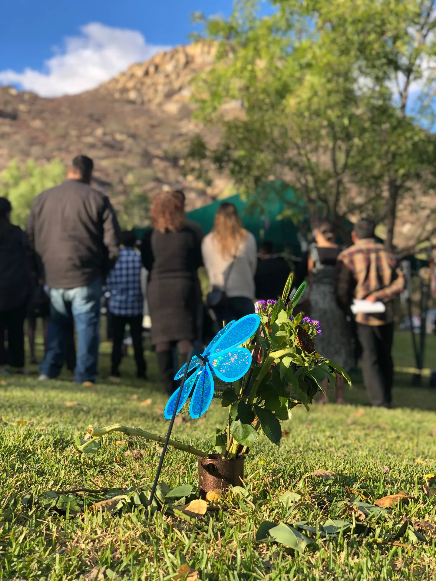 Family gathered at a cemetery honoring a loved one with flowers and memorial decorations
